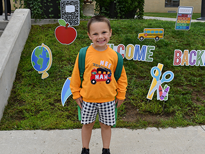 Happy elementary student outside ready for school