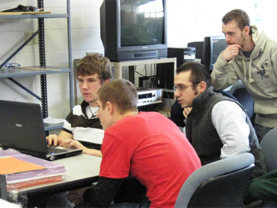 male students huddled around a laptop