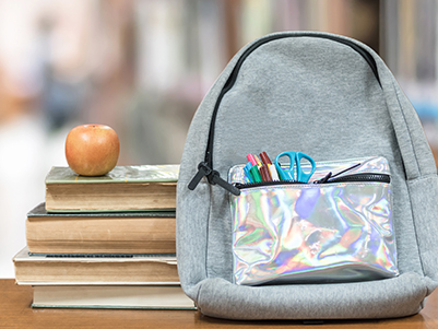 Backpack next to an apple and books