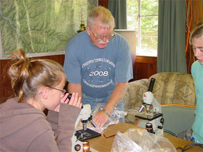 Teacher showing students how to use microscope